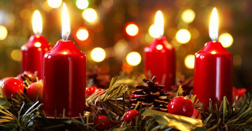 cuatros velas rojas encendidas sobre adornos de navidad luz dorada