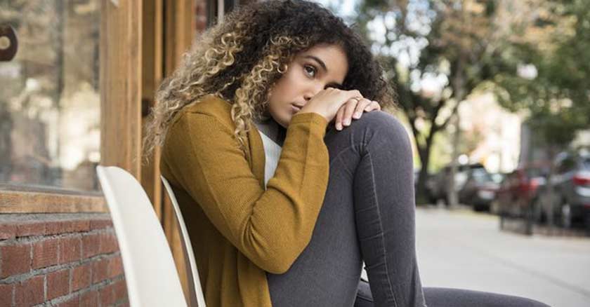 mujer triste sentada en una banca en la acera sola soledad