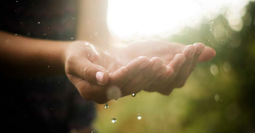 persona poniendo las manos hacia arriba con palmas para sostener agua lluvia