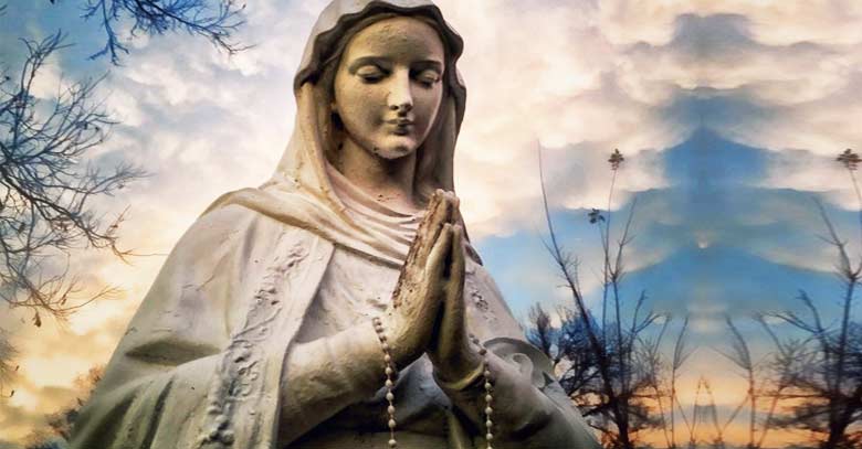 virgen maria madre estatua rezando rosario en mano fondo cielo nubes