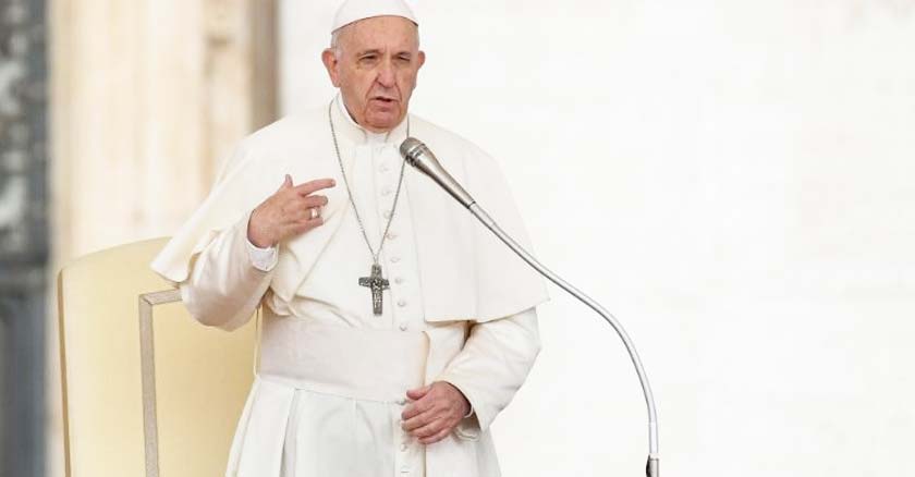 papa francisco delante de microfono hablando de pie fondo blanco   