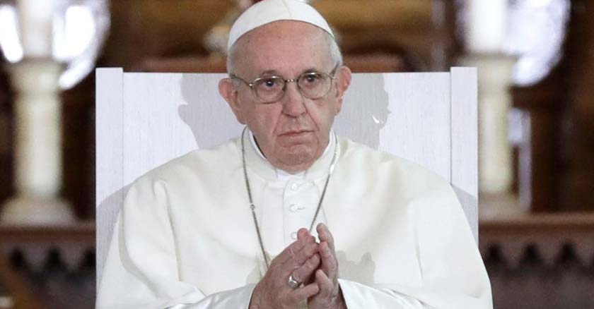 papa francisco sentado tiene las manos juntas mirando hacia el frente 