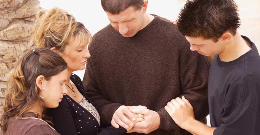 familia tomadas de las manos juntos orando con ojos cerrados dia 