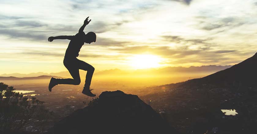 joven dando un salto fondo atardecer luz del sol montanas ciudad