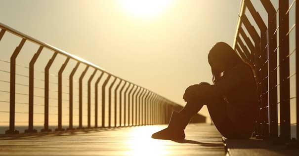 mujer sentada puente ocaso atardecer deprimida 