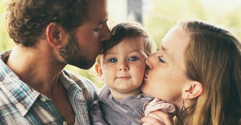 papa y mama besando a su bebe cada uno en mejilla dia 